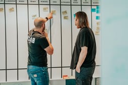 Team members discussing tasks on a board during an Agile coaching session to improve planning and collaboration