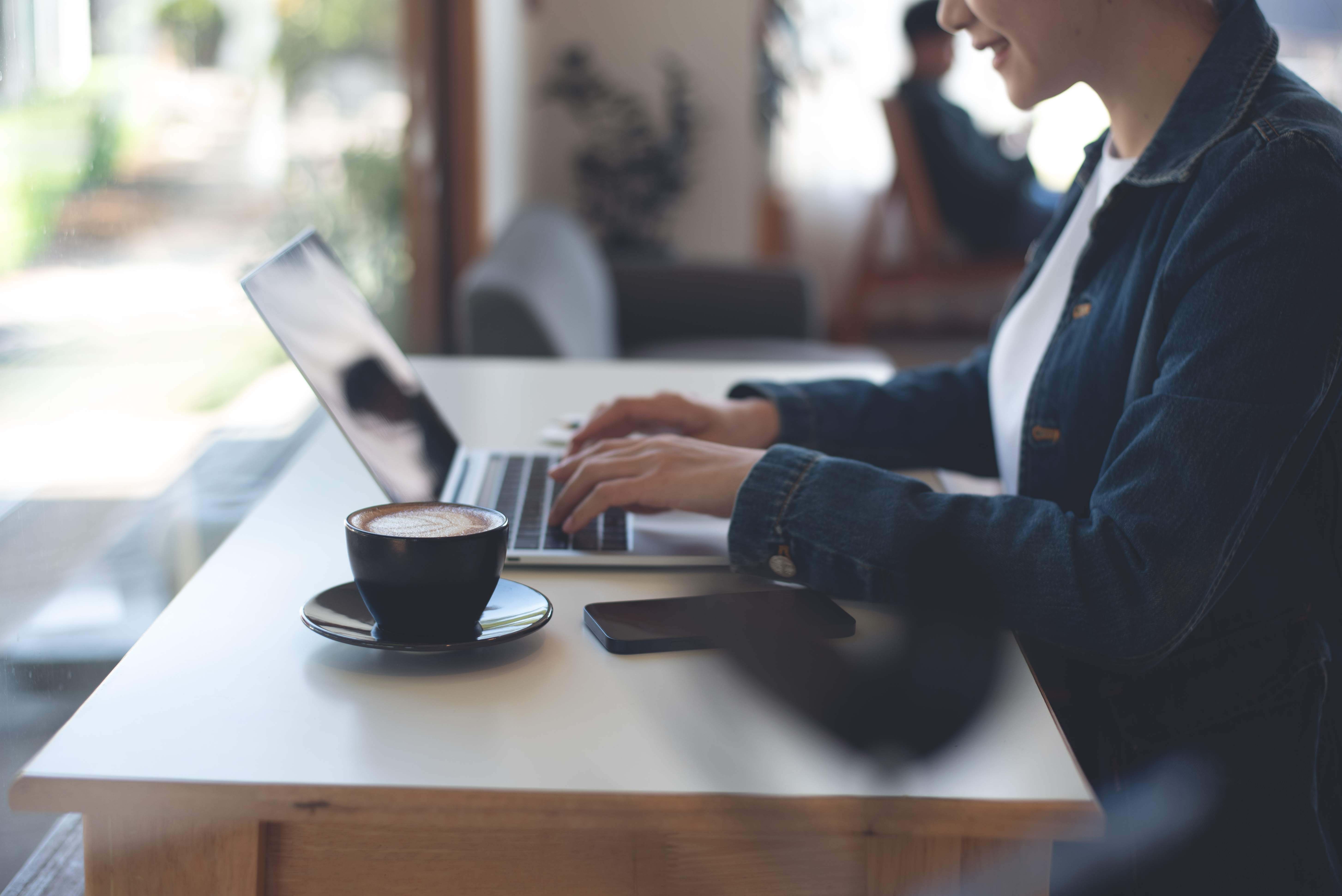 person typing on laptop with coffee - liantis case